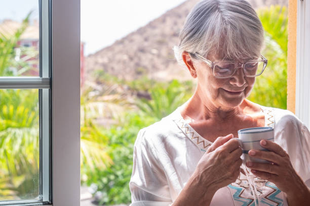 istock Senior woman at the window holding a coffee cup 1331431192