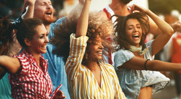 Group of friends dancing at a concert. Closeup side view of group of group young adults having fun at a concert on a summer afternoon. concert stock pictures, royalty-free photos & images