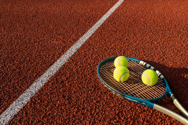 istock Tennis rocket and three balls on it, red court and white line.Empty space 1331437376