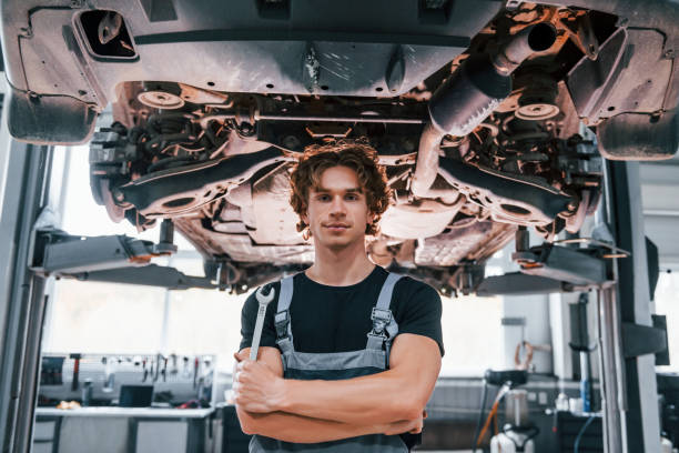 istock Handsome adult man in grey colored uniform standing below automobile 1331439157