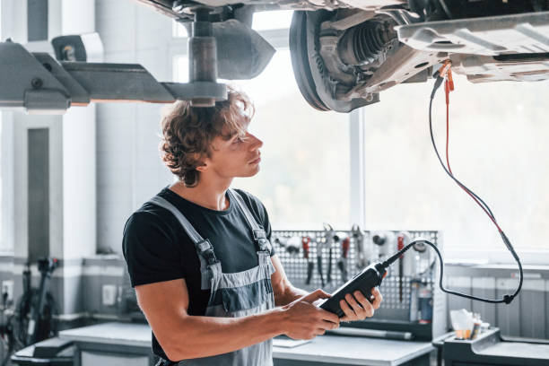 istock Special tool for testing characteristics. Adult man in grey colored uniform works in the automobile salon 1331439375