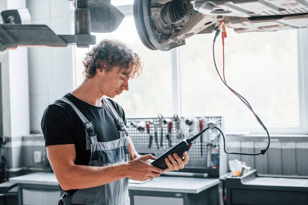 istock Special tool for testing characteristics. Adult man in grey colored uniform works in the automobile salon 1331439486