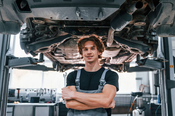 istock Handsome adult man in grey colored uniform standing below automobile 1331439572