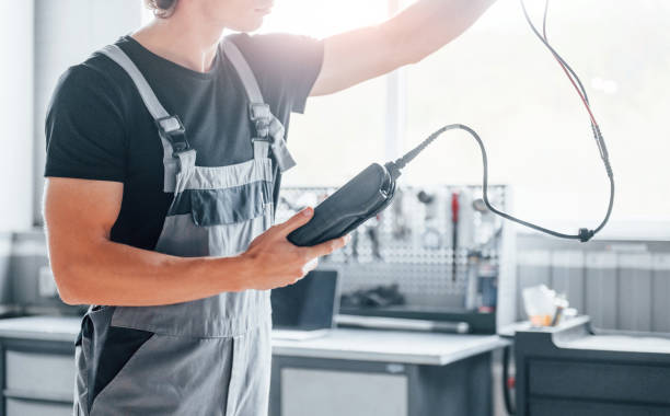 istock Special tool for testing characteristics. Adult man in grey colored uniform works in the automobile salon 1331439623
