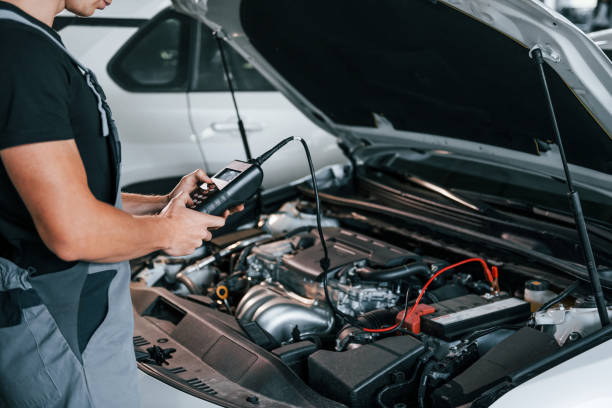 istock Special tool for testing characteristics. Adult man in grey colored uniform works in the automobile salon 1331439641