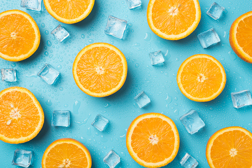 Top view photo of orange slices ice cubes and water drops on isolated light blue background