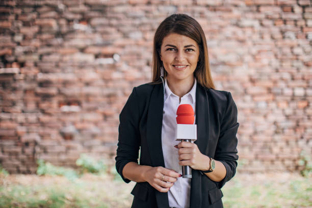 Female reporter talking in front of the camera live in news Female reporter talking in front of the camera and while being live on the news Journalist stock pictures, royalty-free photos & images