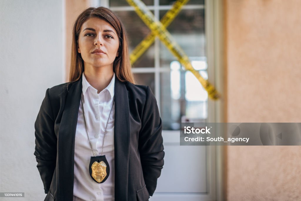Woman detective at the crime scene Portrait of detective in front of crime scene, before giving statement for the press Detective Stock Photo