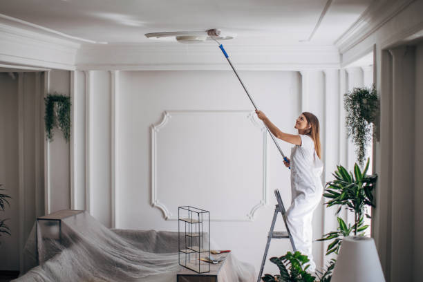 istock Woman painting ceiling with paint roller 1331442436
