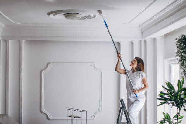 istock Woman painting ceiling with paint roller 1331442451