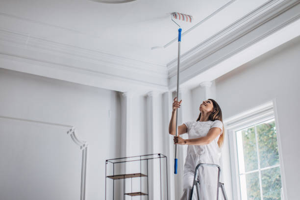 istock Woman painting ceiling with paint roller 1331442470