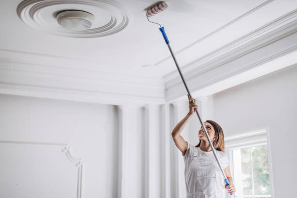 istock Woman painting ceiling with paint roller 1331442514