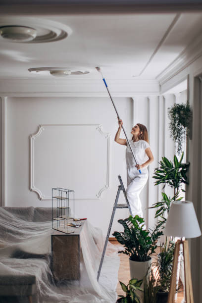 istock Woman painting ceiling with paint roller 1331442564