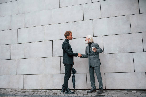 istock Having a meet. Young guy with senior man in elegant clothes is outdoors together. Conception of business 1331445273