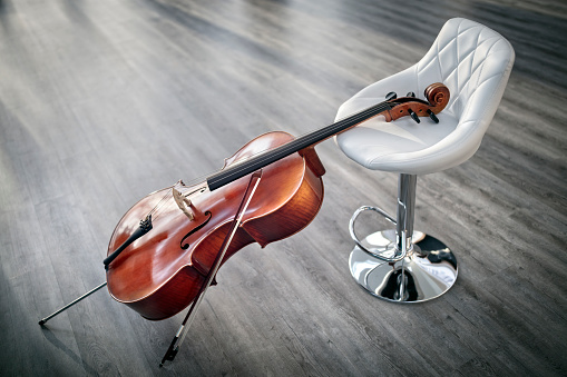 Cello resting against a white chair for classical music concept