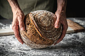 Male hands holding Sourdough bread brown round loaf wholegrain homemade German style
