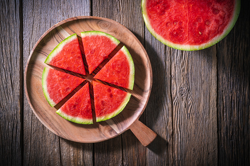 Watermelon fruit slice cut on wooden tray cut in six triangles on vintage wood background