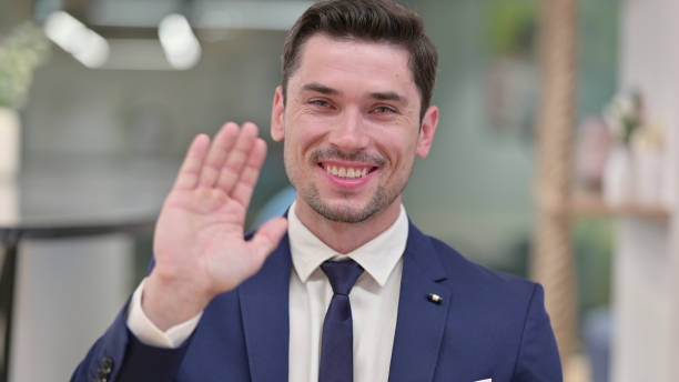 istock Cheerful Young Businessman Waving at the Camera 1331453284