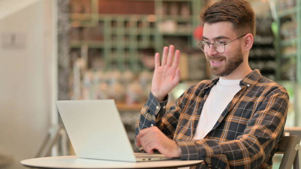 istock Young Man doing Video Call on Laptop in Cafe 1331453880