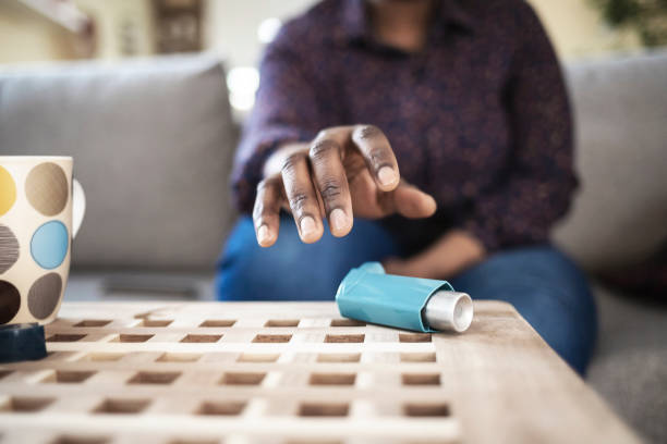 I need my asthma pump Girl suffering asthma attack reaching inhaler sitting on a couch in the living room at home asthma inhaler stock pictures, royalty-free photos & images