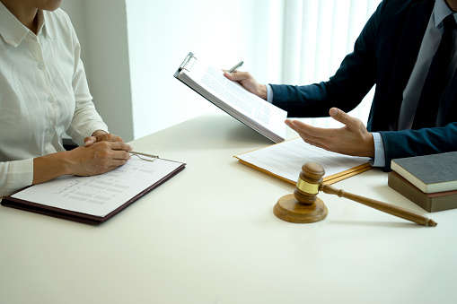 The lawyer is explaining the legal message to a colleague at work on the table there are gavel.