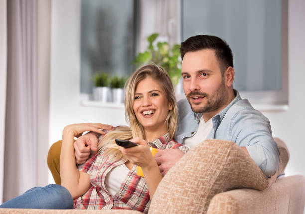 istock Young couple watching tv on sofa at home 1331459382