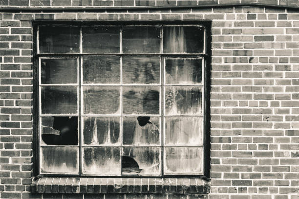 istock Old window with broken panes that has been boarded up. Set n brick wall in warm tone black and white. 1331460116