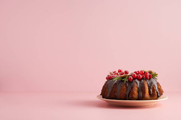 pastel de navidad de fondo rosa. espacio de copia horizontal para texto. pastel con glaseado de chocolate y bayas de grosella roja - fruitcake christmas cake cake christmas fotografías e imágenes de stock