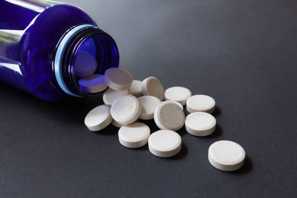 istock White pills spilling out of blue bottle on the table 1331461492