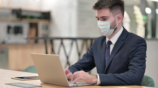 istock Young Businessman with Protective Face Mask working on Laptop 1331469591