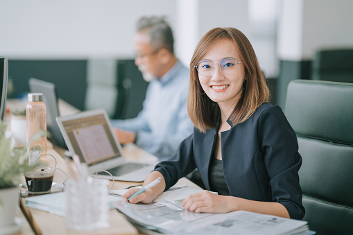 asian chinese woman looking at camera at her place of work smiling with confidence