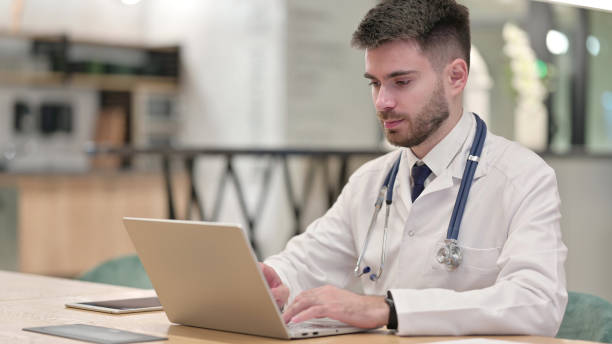 istock Focused Young Doctor Working on Laptop in Clinic 1331469835