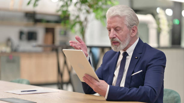 istock Senior Old Businessman doing Video Chat on Tablet at Home 1331470026