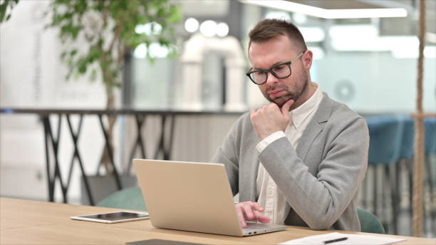 istock Pensive Casual Young Man Thinking and Working on Laptop 1331472807