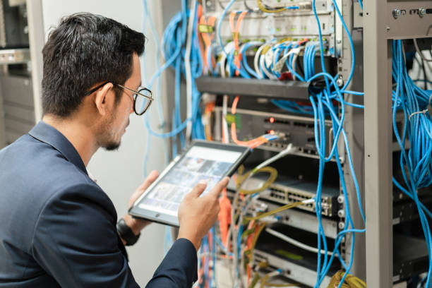 istock Stock photo of a young network technician holding tablet working to connecting network cables in server cabinet in network server room. IT engineer working in network server room 1331478076