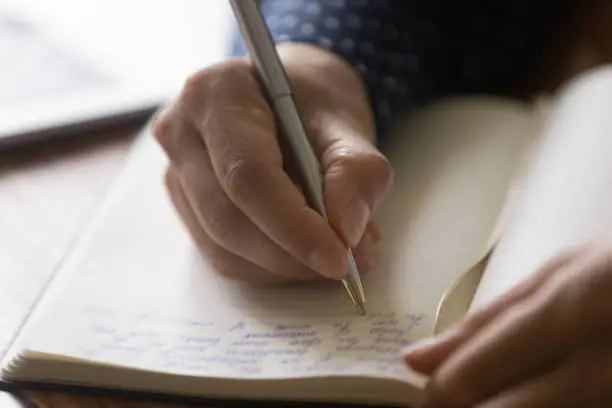 Photo of Hands of woman taking notes of online lecture webinar