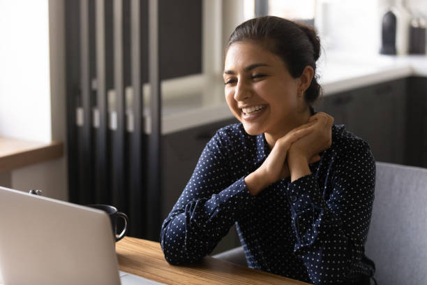 happy indian female employee working at laptop from home - interview evenement stockfoto's en -beelden