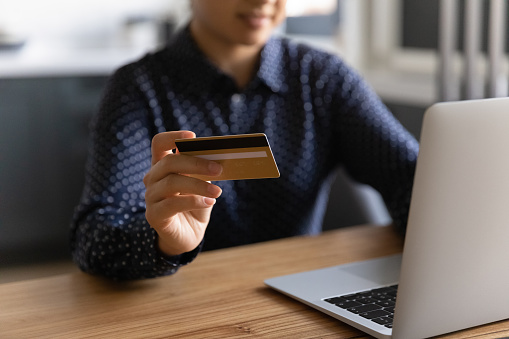 Millennial woman shopping online from home, using laptop for Internet order, paying for purchase by credit card. Shopaholic spending money from account at computer. Banking service concept. Close up