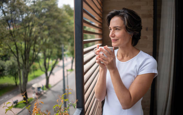 Woman at home drinking her morning coffee while looking out the window