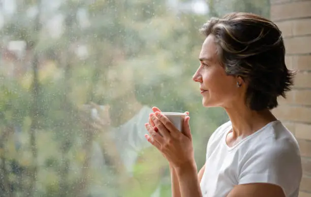 Photo of Woman drinking a cup of coffee while looking out of the window