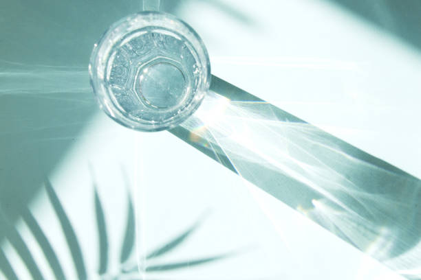 Trendy pattern made with glasses and shadows on blue background. Sunlight through glass of water, palm tree leaf shadows.