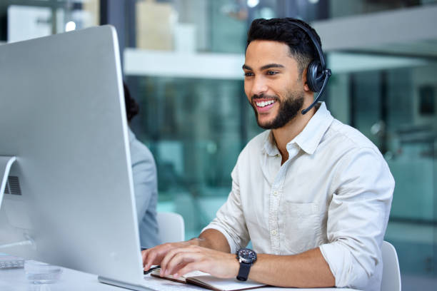 Shot of a businessman using a computer while working in a call center He answers all calls with skill and clarity male customer care stock pictures, royalty-free photos & images