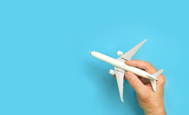 Male hand holding aircraft model, airplane in hand on blue background. Male hand holding model airplane, aircraft on blue turquoise background. Copy space. Top view toy airplane stock pictures, royalty-free photos & images