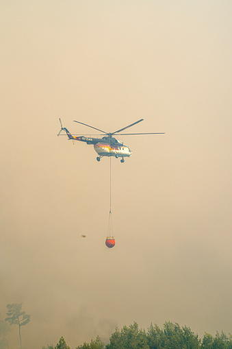 Manavgat, Antalya, Turkey - July 29, 2021: Fire fighting helicopter carry water bucket to the forest fire in Manavgat, Antalya, Turkey