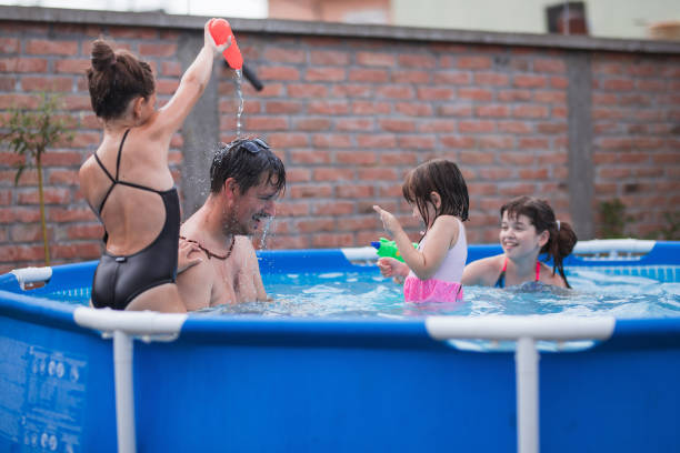 istock Playful children watering their dad at swimming pool 1331501774