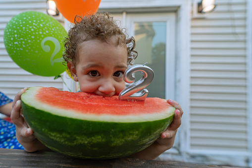 Kid celebrating birthday in a healthy way eating a watermelon