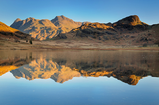 Dawn at Blea Tarn with the Langdale Pikes reflected in the water.