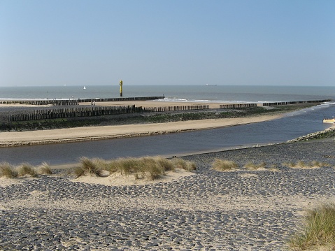 a seascape at the dutch coast in cadzand with a drainage canal in front of scheldt river with its sandy beaches