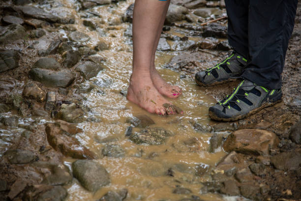 Feet in the water. People crossing muddy river in spring