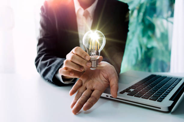 istock The hand of a man with a light bulb And there is a gear icon in it And he is using a notebook computer. The idea of 